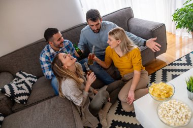 Neşeli bir grup arkadaş televizyonda futbol maçı izliyor. Genç taraftarlar televizyonda futbol maçı izliyor..