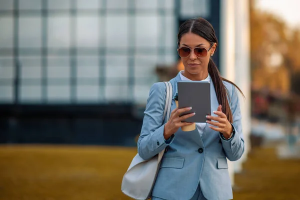 Attractive smiling woman using tablet in front of her office.People,business and technology concept.