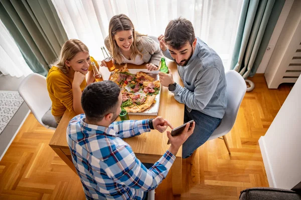 Group of friends eating pizza together at home.People,lifestyle and junk food concept.