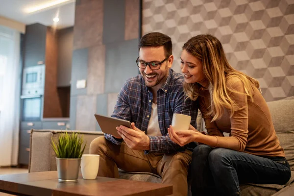 Evde genç bir çift var. Mutlu çift online alışveriş için tablet kullanıyor.