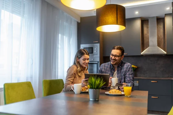 Evde genç bir çift var. Mutlu çift online alışveriş için tablet kullanıyor.