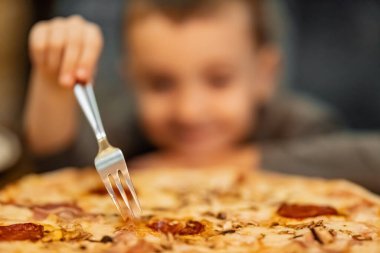 Evde pizza yiyen küçük bir çocuk. İnsanlar, yemek ve yaşam tarzı kavramı. Kapatın..