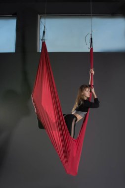 Yoga sinek. Genç kadın fitness club gri arka plan üzerinde bir hamakta ile hava Anti-yerçekimi yoga uygulamaları.