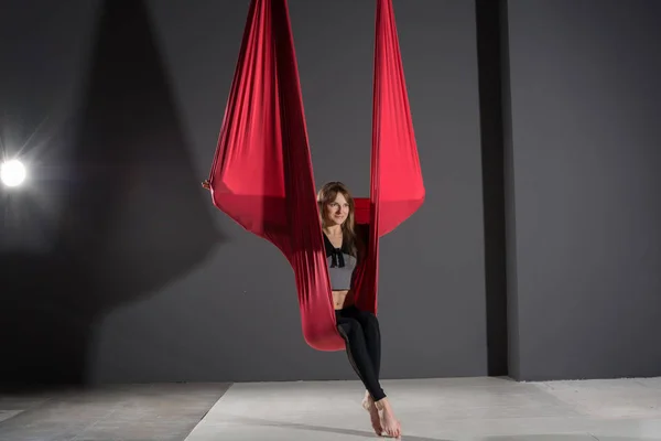 Yoga sinek. Genç kadın fitness club gri arka plan üzerinde bir hamakta ile hava Anti-yerçekimi yoga uygulamaları.