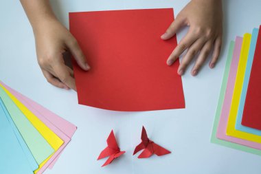 Beyaz arka plan üzerinde renkli kağıttan origami kelebek çocuk ellerin yaptığını. ders origami kelebek.
