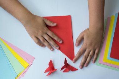 Beyaz arka plan üzerinde renkli kağıttan origami kelebek çocuk ellerin yaptığını. ders origami kelebek.