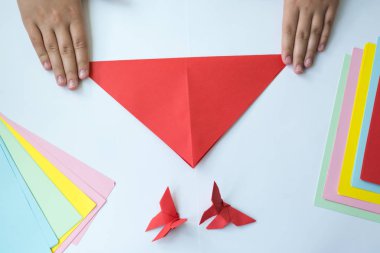 Beyaz arka plan üzerinde renkli kağıttan origami kelebek çocuk ellerin yaptığını. ders origami kelebek.
