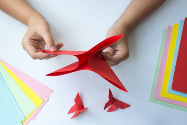 Beyaz arka plan üzerinde renkli kağıttan origami kelebek çocuk ellerin yaptığını. ders origami kelebek.