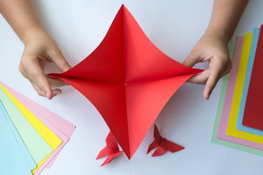 Beyaz arka plan üzerinde renkli kağıttan origami kelebek çocuk ellerin yaptığını. ders origami kelebek.
