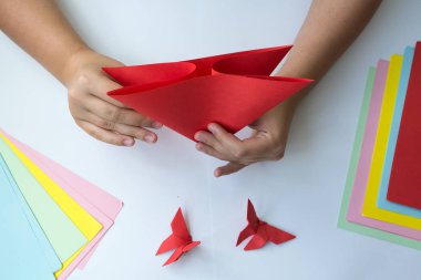 Beyaz arka plan üzerinde renkli kağıttan origami kelebek çocuk ellerin yaptığını. ders origami kelebek.