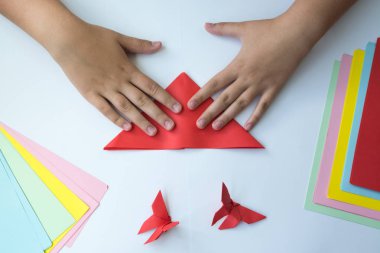 Beyaz arka plan üzerinde renkli kağıttan origami kelebek çocuk ellerin yaptığını. ders origami kelebek.