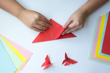 Beyaz arka plan üzerinde renkli kağıttan origami kelebek çocuk ellerin yaptığını. ders origami kelebek.
