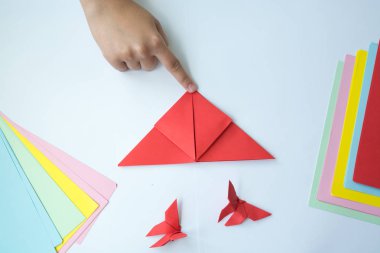 Beyaz arka plan üzerinde renkli kağıttan origami kelebek çocuk ellerin yaptığını. ders origami kelebek.