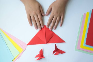 Beyaz arka plan üzerinde renkli kağıttan origami kelebek çocuk ellerin yaptığını. ders origami kelebek.