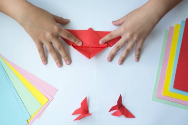 Beyaz arka plan üzerinde renkli kağıttan origami kelebek çocuk ellerin yaptığını. ders origami kelebek.
