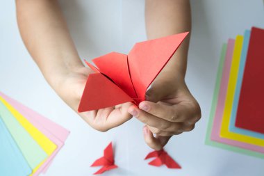 Beyaz arka plan üzerinde renkli kağıttan origami kelebek çocuk ellerin yaptığını. ders origami kelebek.