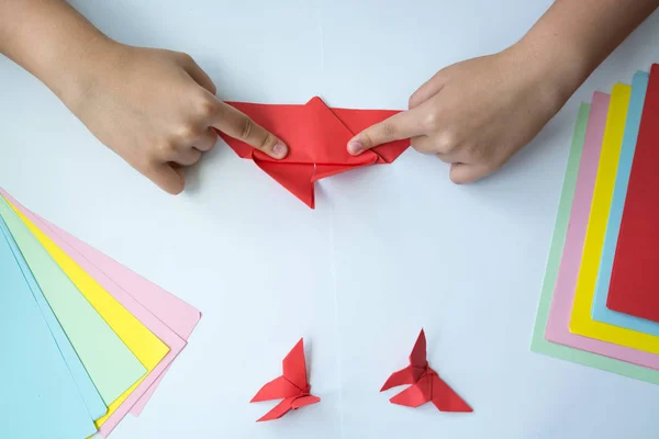 Beyaz arka plan üzerinde renkli kağıttan origami kelebek çocuk ellerin yaptığını. ders origami kelebek.