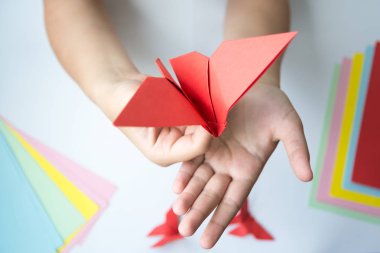 Beyaz arka plan üzerinde renkli kağıttan origami kelebek çocuk ellerin yaptığını. ders origami kelebek.