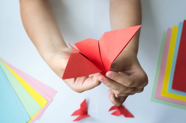 Beyaz arka plan üzerinde renkli kağıttan origami kelebek çocuk ellerin yaptığını. ders origami kelebek.