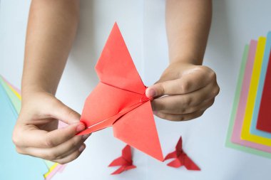 Beyaz arka plan üzerinde renkli kağıttan origami kelebek çocuk ellerin yaptığını. ders origami kelebek.