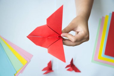 Beyaz arka plan üzerinde renkli kağıttan origami kelebek çocuk ellerin yaptığını. ders origami kelebek.