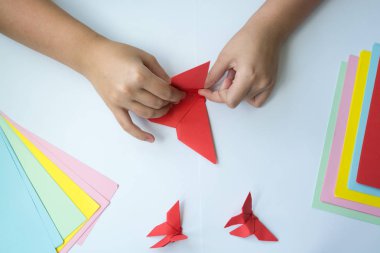 Beyaz arka plan üzerinde renkli kağıttan origami kelebek çocuk ellerin yaptığını. ders origami kelebek.