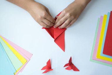 Beyaz arka plan üzerinde renkli kağıttan origami kelebek çocuk ellerin yaptığını. ders origami kelebek.