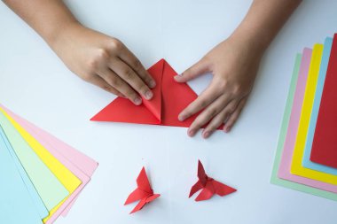 Beyaz arka plan üzerinde renkli kağıttan origami kelebek çocuk ellerin yaptığını. ders origami kelebek.