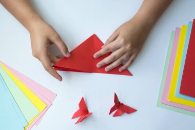 Beyaz arka plan üzerinde renkli kağıttan origami kelebek çocuk ellerin yaptığını. ders origami kelebek.