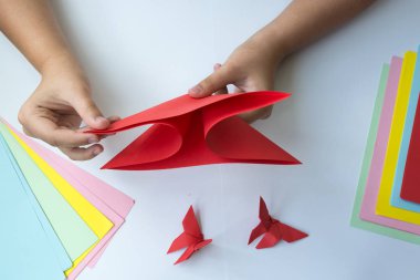 Beyaz arka plan üzerinde renkli kağıttan origami kelebek çocuk ellerin yaptığını. ders origami kelebek.