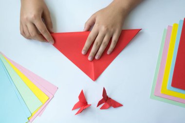 Beyaz arka plan üzerinde renkli kağıttan origami kelebek çocuk ellerin yaptığını. ders origami kelebek.