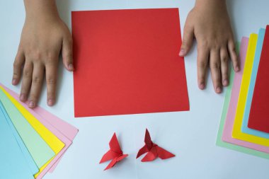 Beyaz arka plan üzerinde renkli kağıttan origami kelebek çocuk ellerin yaptığını. ders origami kelebek.