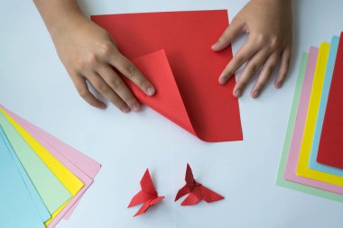 Beyaz arka plan üzerinde renkli kağıttan origami kelebek çocuk ellerin yaptığını. ders origami kelebek.