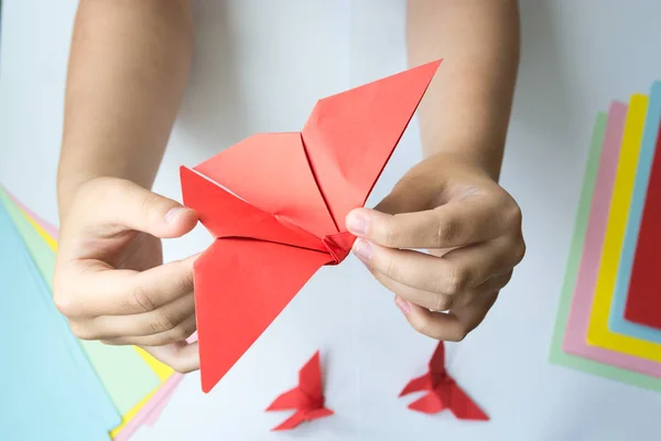 Beyaz arka plan üzerinde renkli kağıttan origami kelebek çocuk ellerin yaptığını. ders origami kelebek.