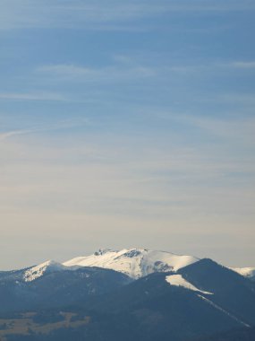 Dağlarla ve mavi gökyüzüyle sabah manzarası. Akşamüstü ufukta beyaz kar ve bulutlarla tepede.