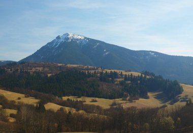 Dağlarla sabah manzarası ve güneş doğarken mavi gökyüzü. Akşamüstü ufukta beyaz kar ve yeşil çayırlı tepelerde.