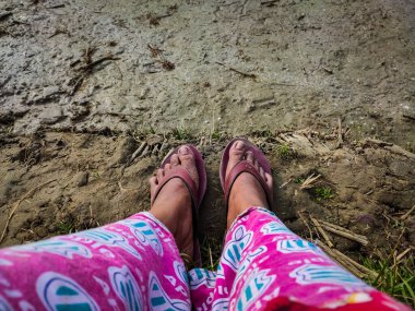 Bir kızın ayakları, kış sabahı güneşin battığı çamurlu toprağa konur..