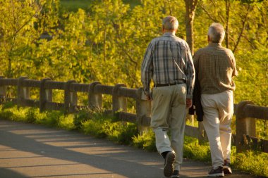 Parkta yürüyen yaşlı insanlar.