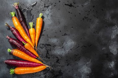 Havuç, turuncu ve mor anthocyanin zengini. Yıkanmış beton zemin, fotokopi alanı ve üst görünümü var.