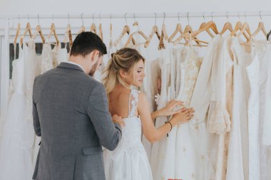 Damat gelinin gelinlik giymesine yardım ediyor. Düğün stüdyosu.