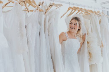 Güzel genç sarışın kadın ayakta bir gelinlik seçimi.