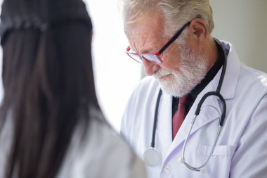 Stetoskop lu kıdemli doktor ve kadın doktor ön planda.