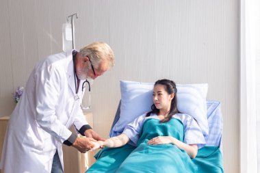 Doktor, hastanede yatan bir hastanın nabzını kontrol ediyor.