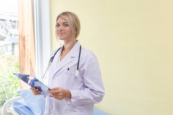 Kobieta lekarz stojący folder gospodarstwa w pokoju pacjenta w szpitalu — Zdjęcie stockowe
