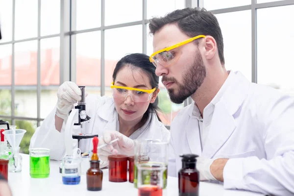 Zwei Wissenschaftler betrachten Chemikalien unter dem Mikroskop in einem Labor — Stockfoto