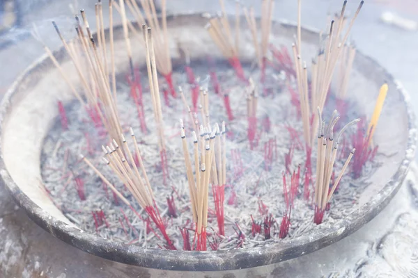 burning incense sticks in a decorated bowl.