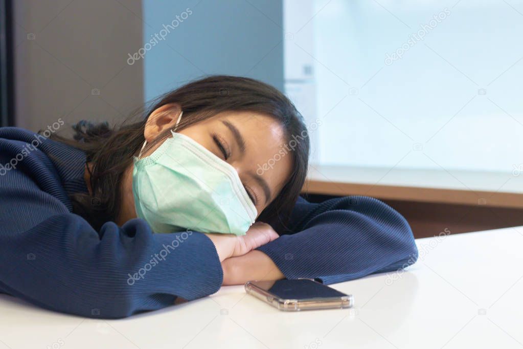 young asian women in being sick Wearing Protective mask Various germs. seatting in office.