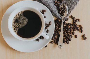 ahşap masada beyaz fincan ve kahve fasulye kahve