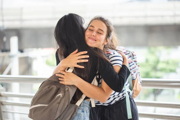 Happy meeting of two friends hugging in the city.