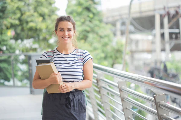 Genç kadın kitap dışarıda ayakta tutuyor. çalışma olacak